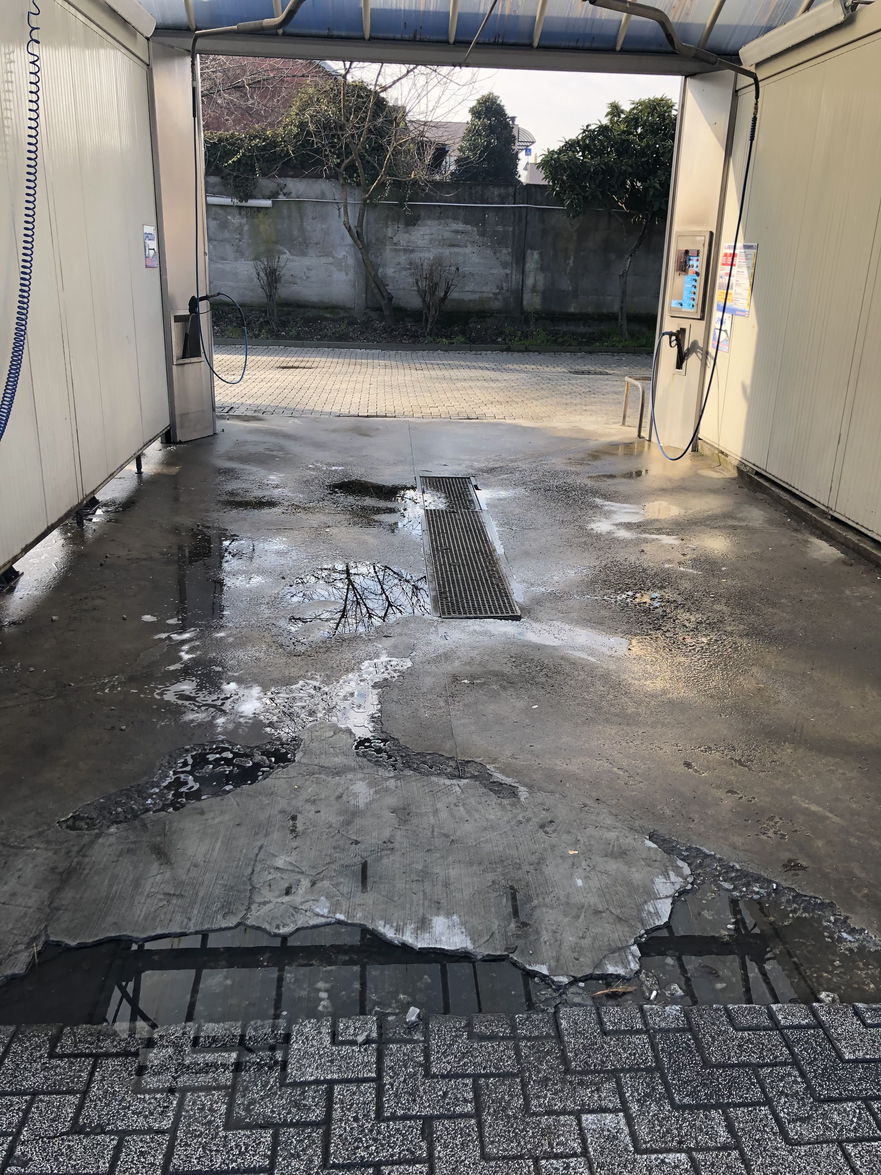 Pavimento autolavaggio gravemente deteriorato con sollevamenti e danni prima dell'intervento RealeResine